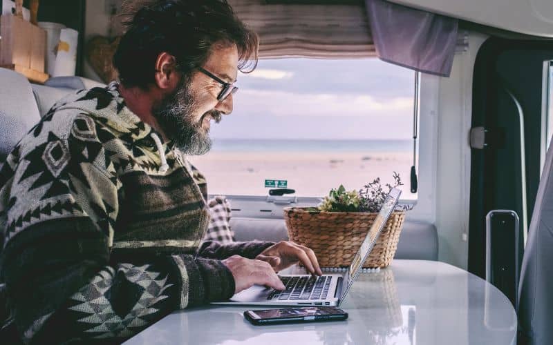 Man working on a laptop at an RV dinette