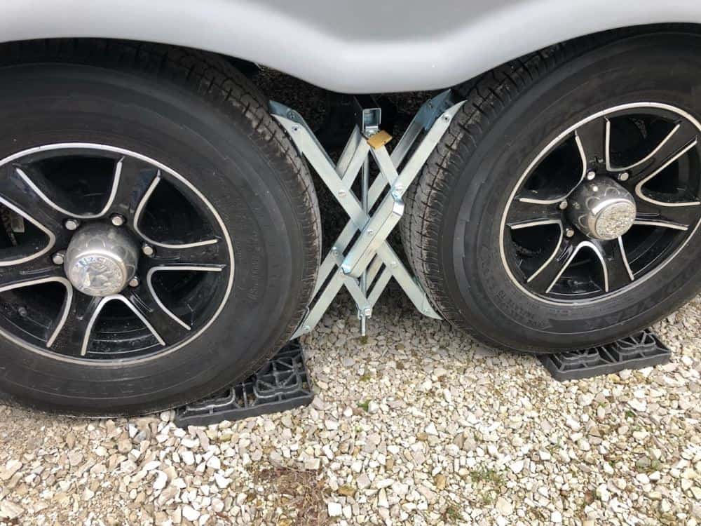 Dual axle RV with X style wheel chock between the tires - new travel trailer gear
