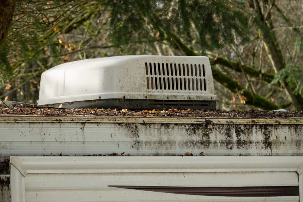 Travel trailer A/C unit covered in leaves and debris